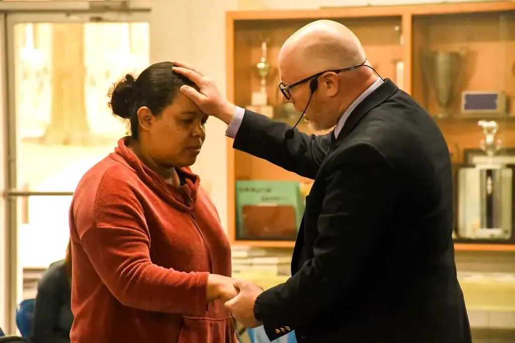 Pastor praying over a member during service